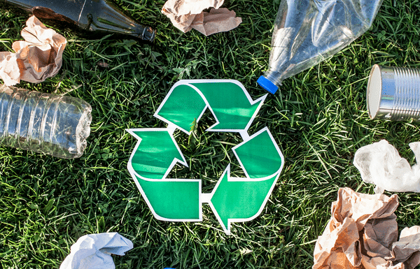 Teaching My Kids About Recycling Recycling symbol with garbage on grass.