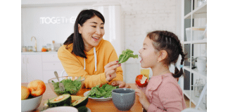 The Best Vermont Spring Foods You Can’t Miss a woman feeding a little girl fresh salad greens