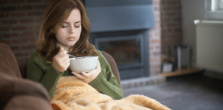 a woman east soup on her couch