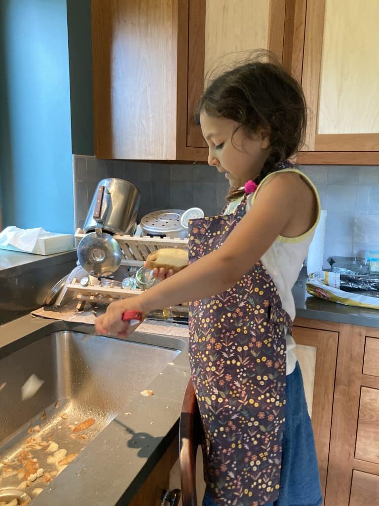 child stands on a chair at the sink