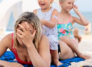 The Excruciating Pressure of Modern Motherhood mom holding her head while two children sit on her pressure of modern motherhood