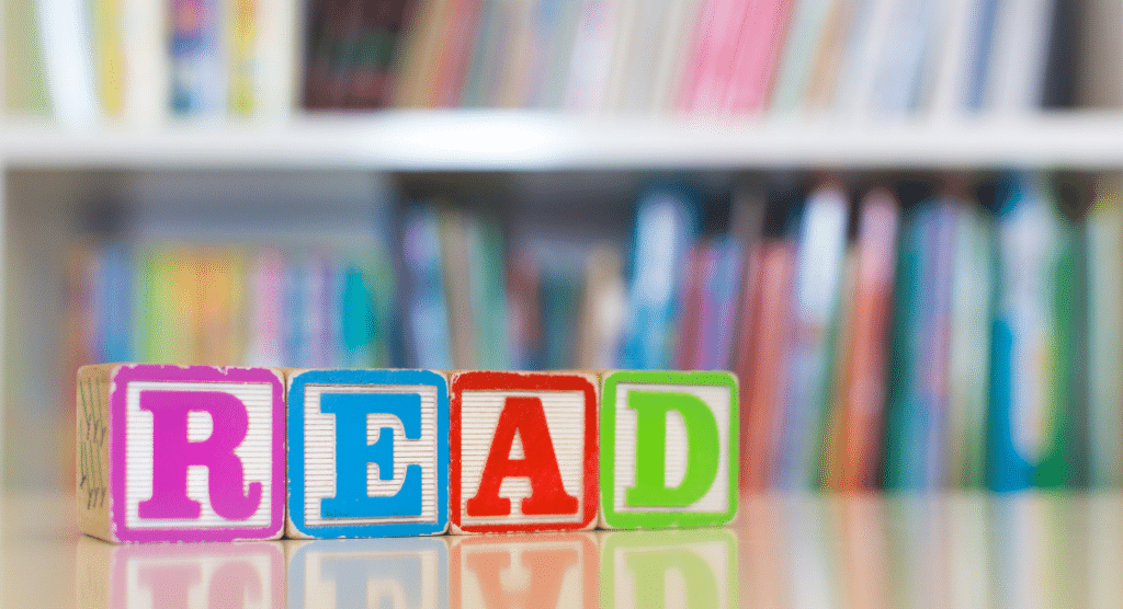 blocks spell out the word read in front of book shelves