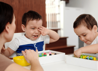 My Decision to Stop at Two Kids A mom sits at a table with her two kids.