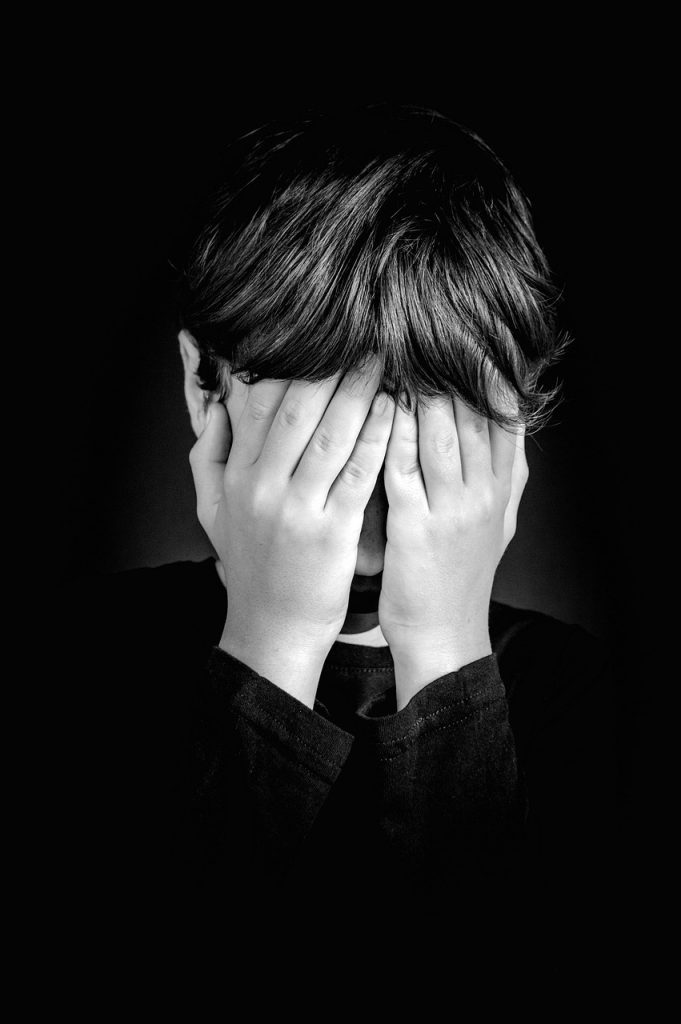woman with her face in her hands in shame