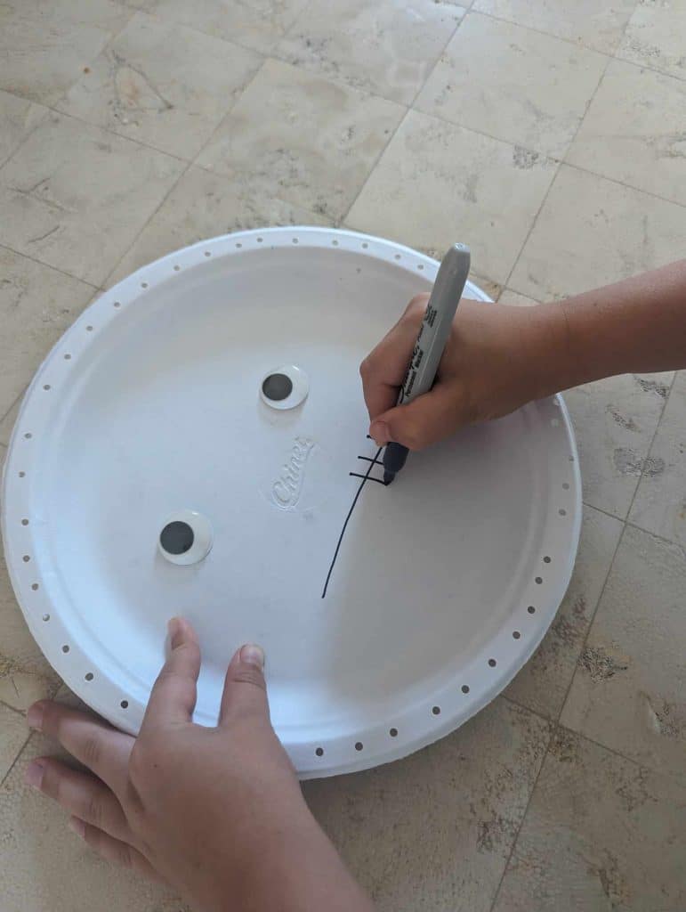 white paper plates and needed tools to make a Halloween mummy craft with your child