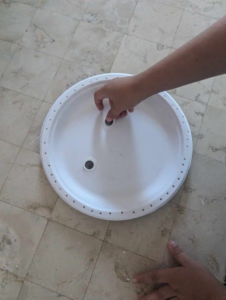 gluing eyes onto a paper plate mummy for a Halloween themed craft