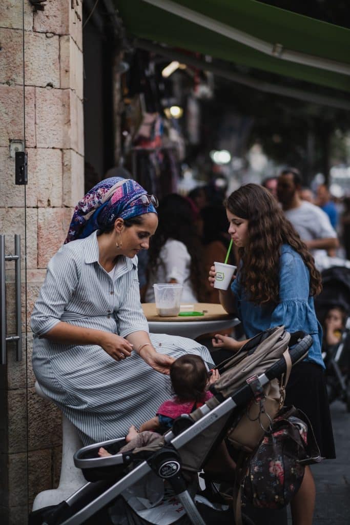 Jewish mom with a pre-teen daughter and a toddler in a stroller at an outdoor cafe