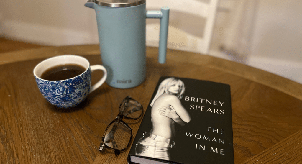 The Britney Spears memoir on a table with a French press and a cup of coffee.