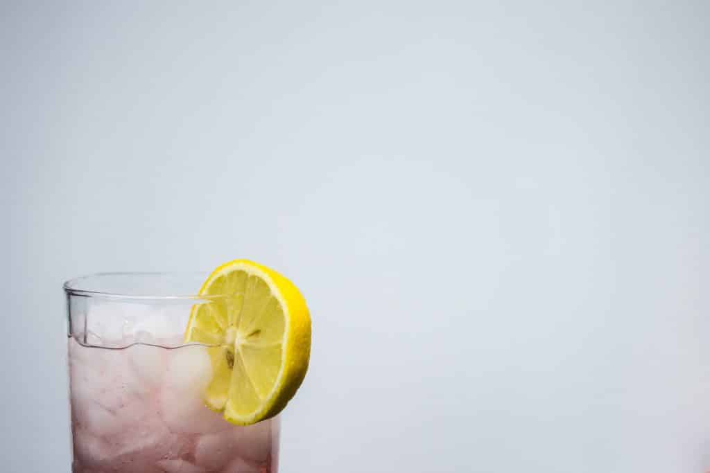pale pink mocktail infused with healing herbs, garnished with a slice of lemon