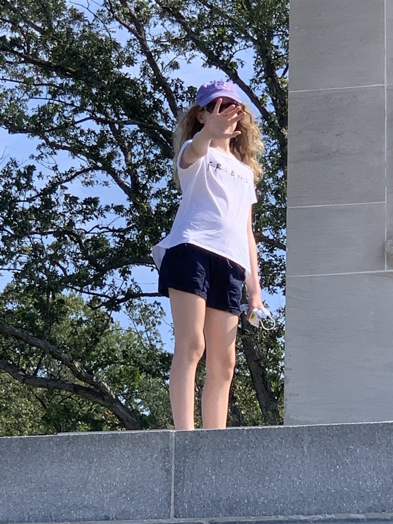 young woman puts her hand up in front of her face in a pose that expresses "stop"