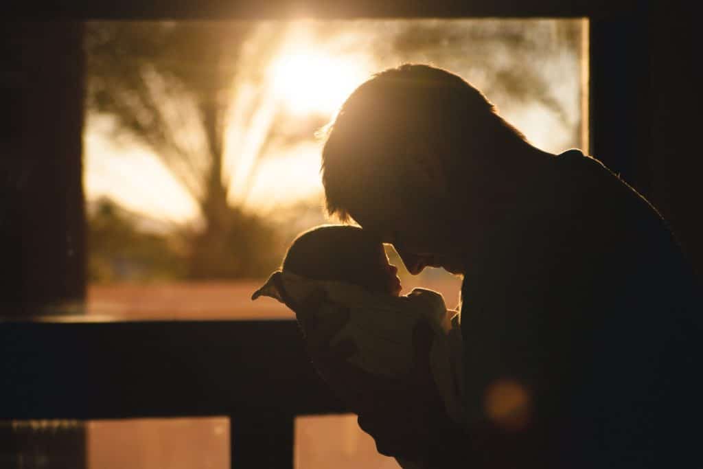 Dad holding newborn baby in loving embrace hoping he can be the best parent ever for his child.