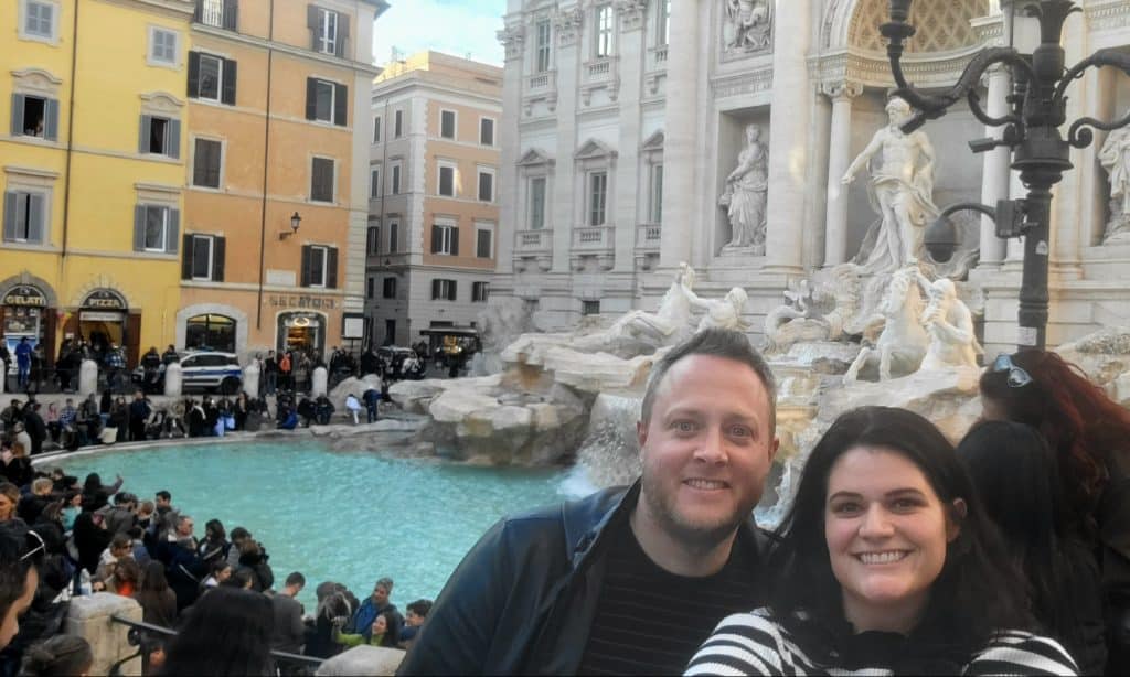 Man and woman in front of the Trevi fountain in Italy
