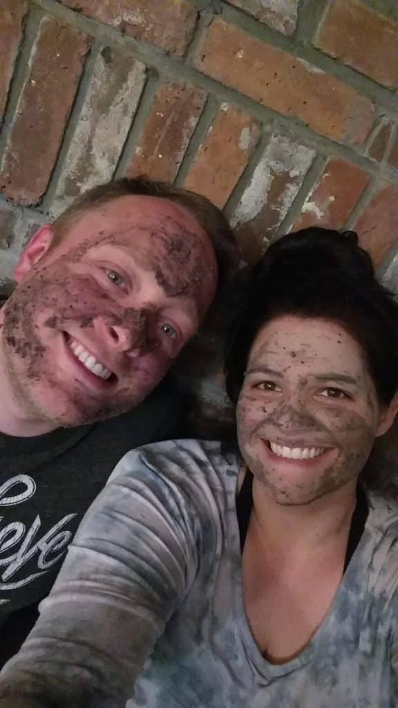 man and woman smiling while wearing mud masks