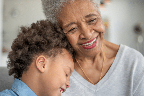 Older woman hugging a young boy. Both are smiling and happy.