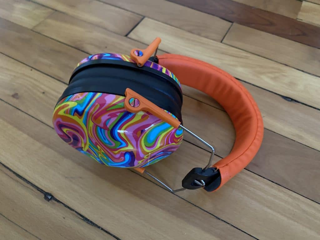 Sound protection headphones for kids, with an orange headband and multicolor ear pieces.