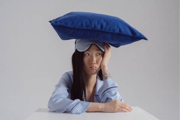 a tired woman with a pillow on top of her head. sleepless mom