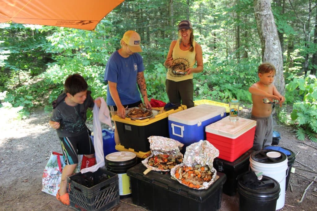 Water Wanderings campers of all ages gather around food they've prepared together for a meal