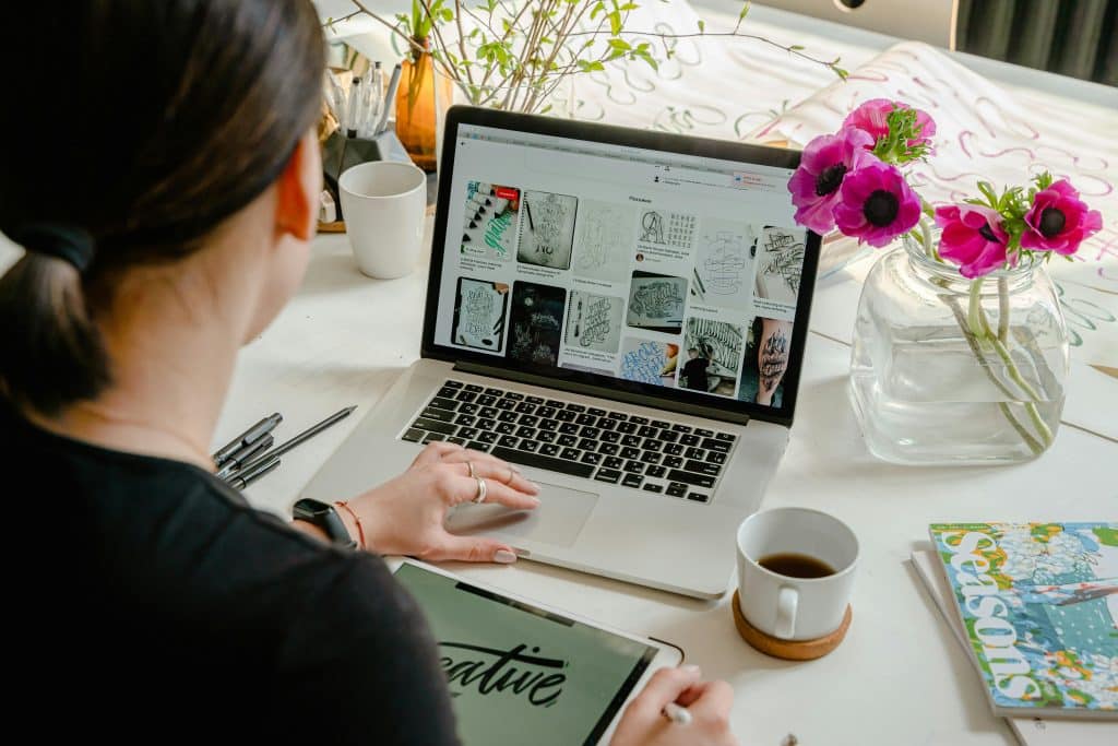 back of woman who is sitting in front of a laptop working