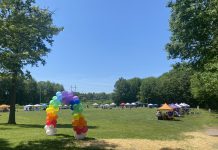 Celebrating Pride as a Queer Mom Rainbow balloon arch leads to a field with vendor tents around the edge.