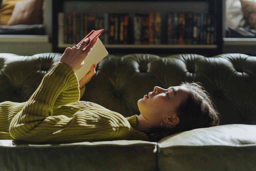 child reading on her back on a sofa