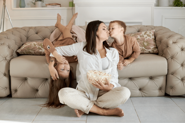Mom sitting with her kids on the couch with popcorn.
