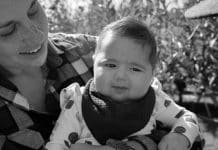 Nonbinary Mom in a Woman’s World the author holding their youngest daughter in an apple orchard