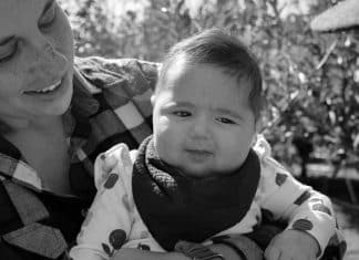 Nonbinary Mom in a Woman’s World the author holding their youngest daughter in an apple orchard