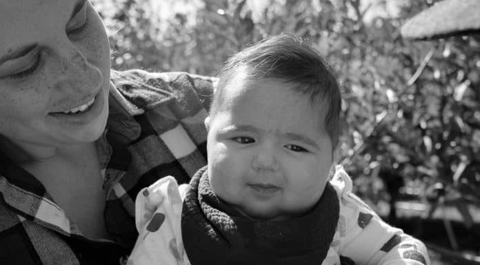 the author holding their youngest daughter in an apple orchard