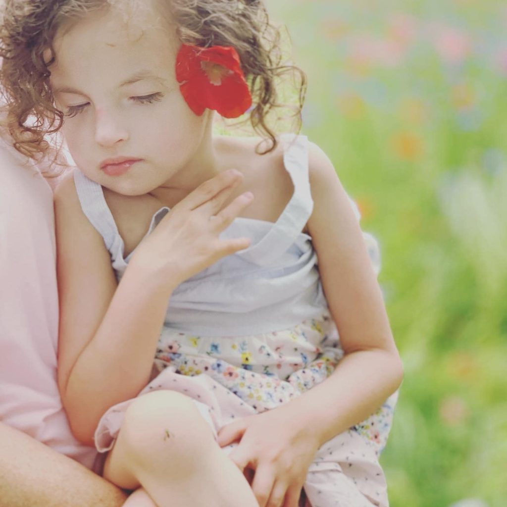 beautiful young girl being held. Her eyes are closed.