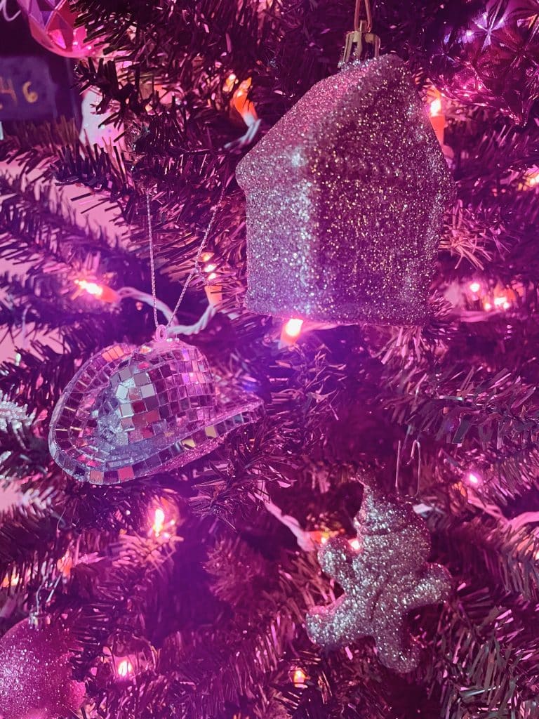 sparkly ornaments on a Christmas tree with pink lights
