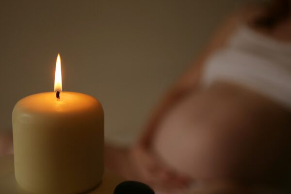 candle, pregnant person in background