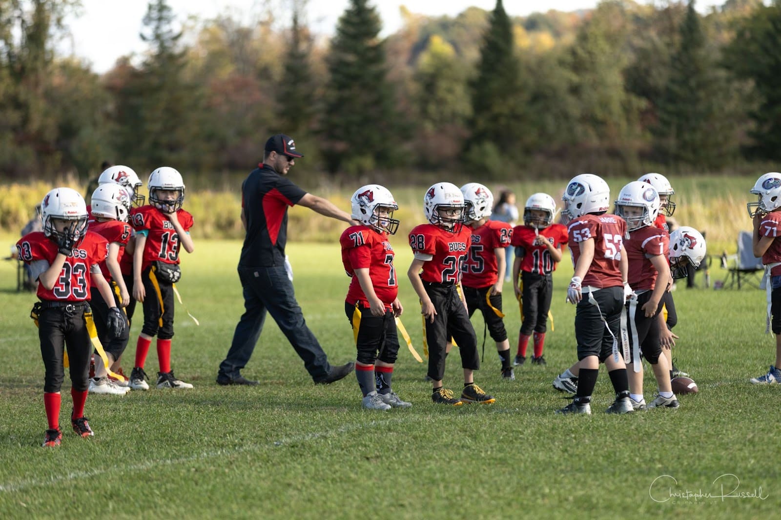 Football coach on the field directing a team of youth football players during a game