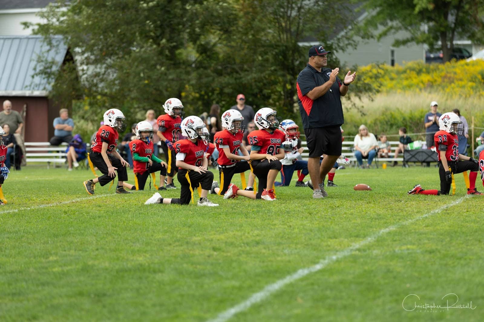 Flag football team kneeling with their coach