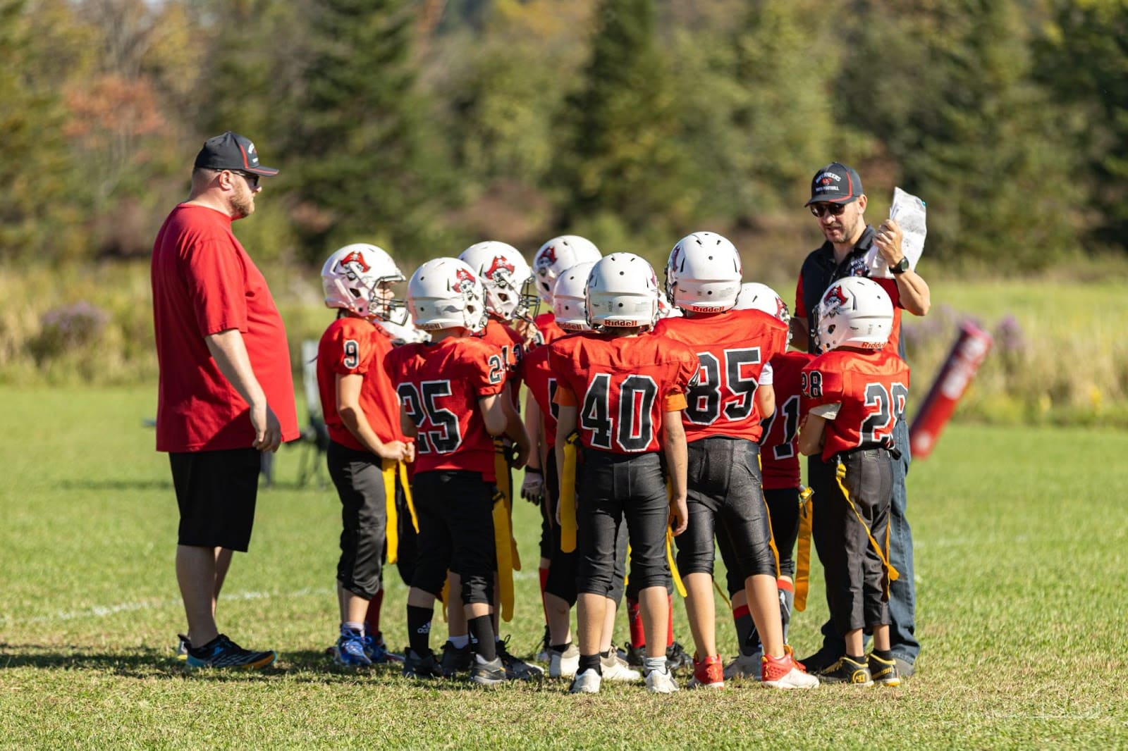 Football coaches in a huddle with their youth football team