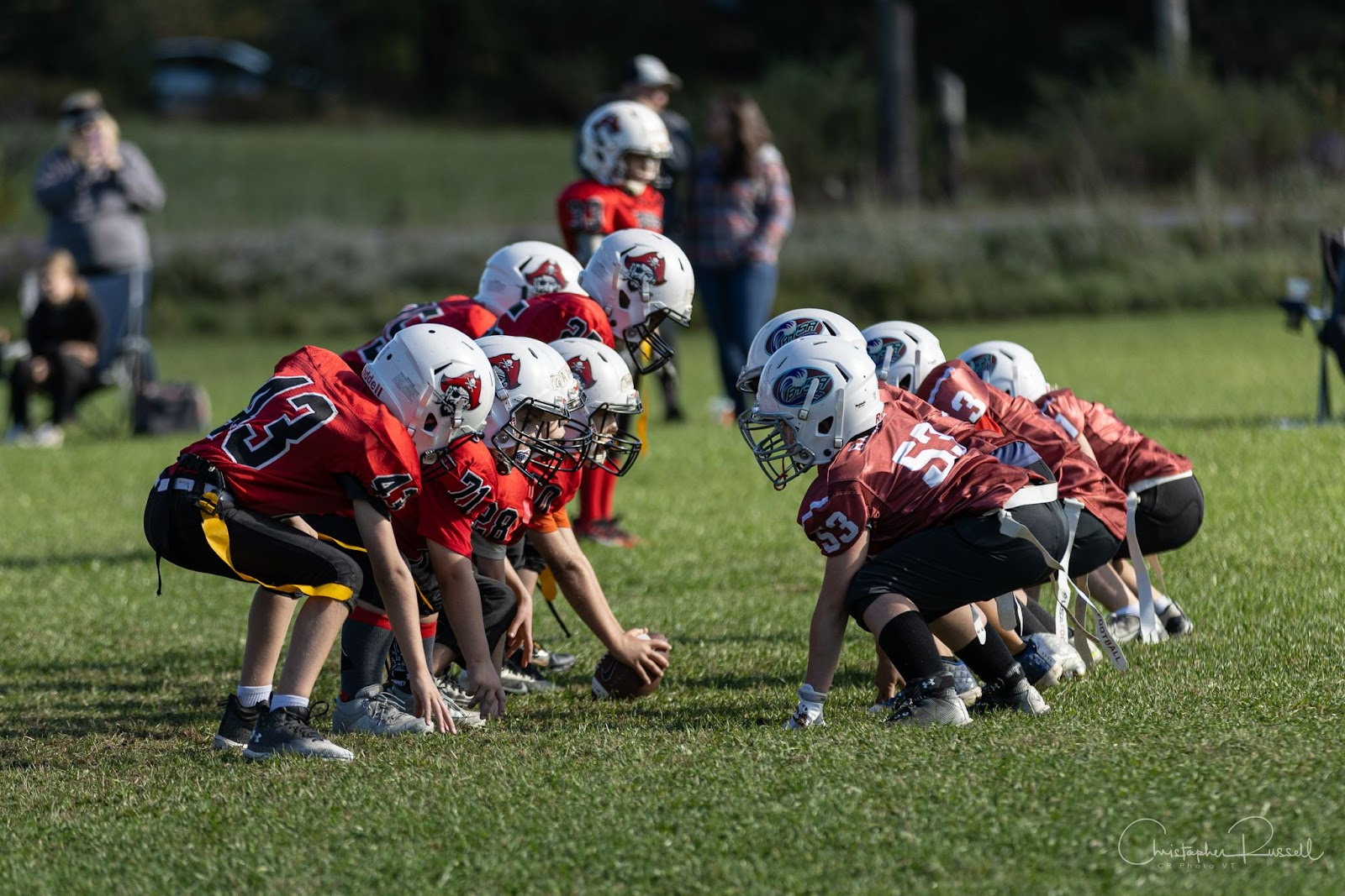 Youth football players crouched and facing the opposing team