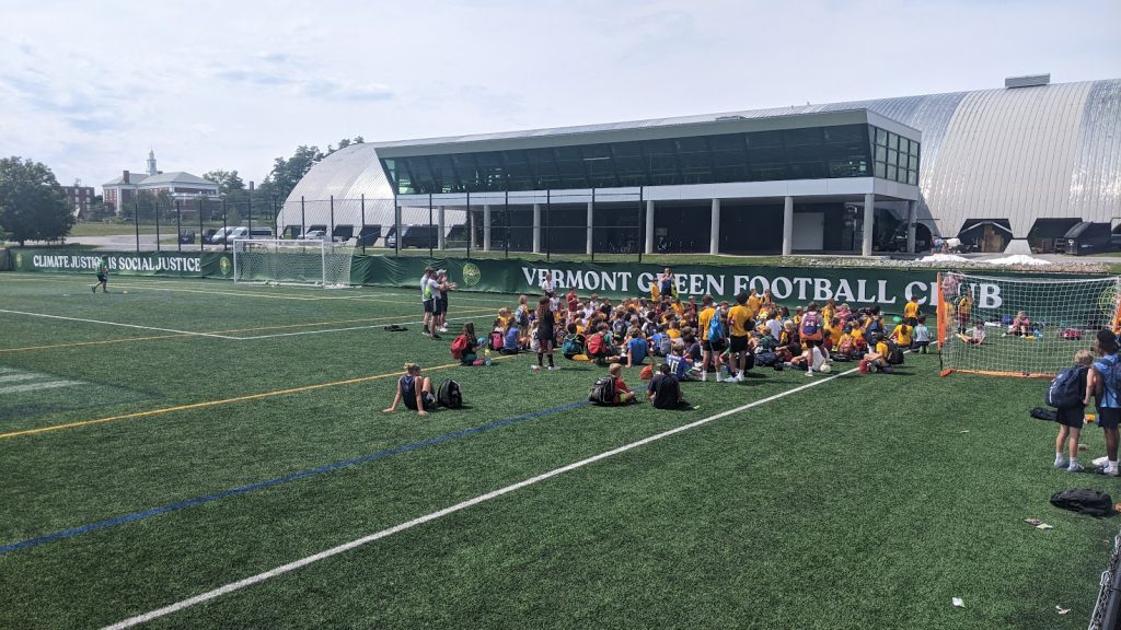 a large group of kids at soccer camp on a soccer field called Virtue Field at the University of Vermont