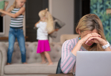 The State of Modern Motherhood: How Bad Is It? Mom trying to work on her laptop while her kids jump behind her.