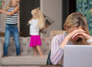 The State of Modern Motherhood: How Bad Is It? Mom trying to work on her laptop while her kids jump behind her.