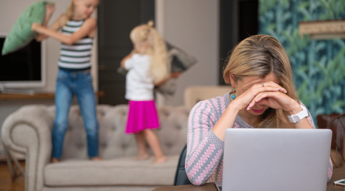 The State of Modern Motherhood: How Bad Is It? Mom trying to work on her laptop while her kids jump behind her.