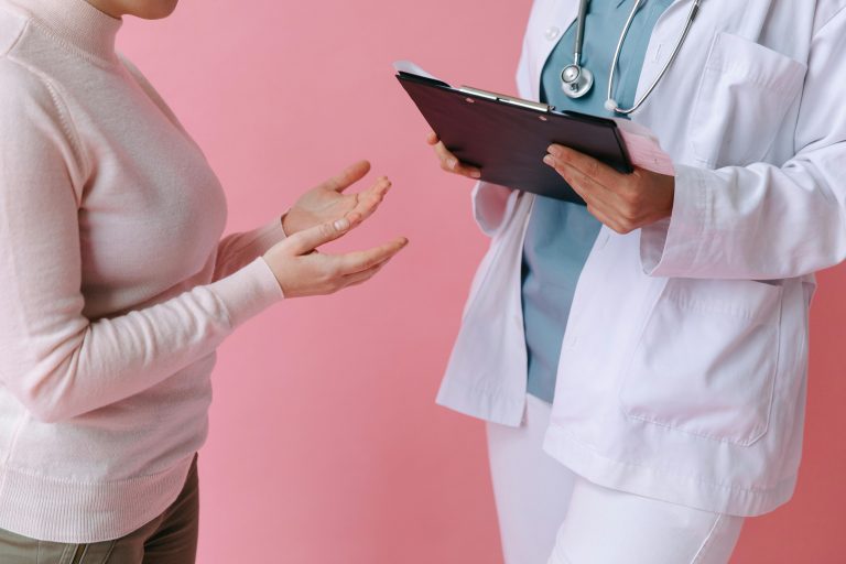 Doctor holding a clipboard talking to a woman